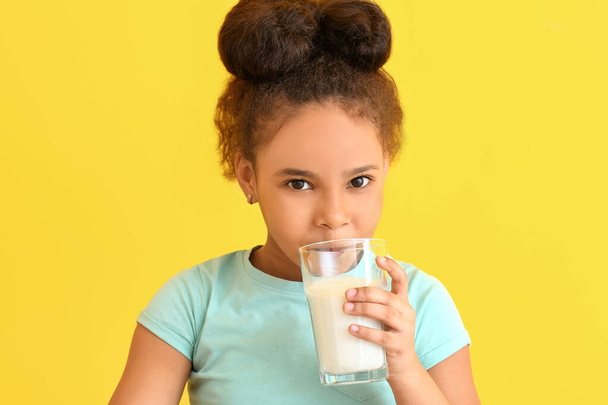 Little African-American girl with milk on color background - Fotó, kép