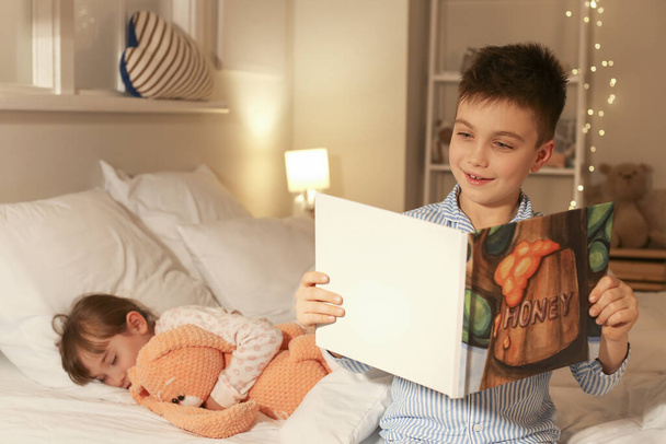 Menina adormecendo enquanto seu irmão lendo a história de dormir em casa
 - Foto, Imagem