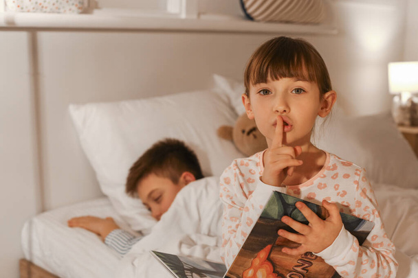 Petit garçon qui s'endort pendant que sa sœur lit l'histoire du coucher à la maison
 - Photo, image