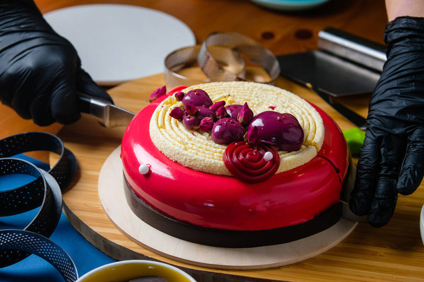 Konditor schneidet einen trendigen Moussekuchen. Zubereitung des modernen Desserts. - Foto, Bild