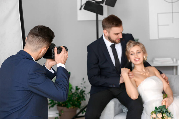 Fotógrafo trabajando con joven pareja de boda en estudio
 - Foto, imagen
