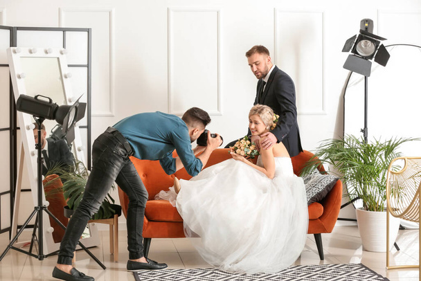 Photographer working with young wedding couple in studio - Fotó, kép