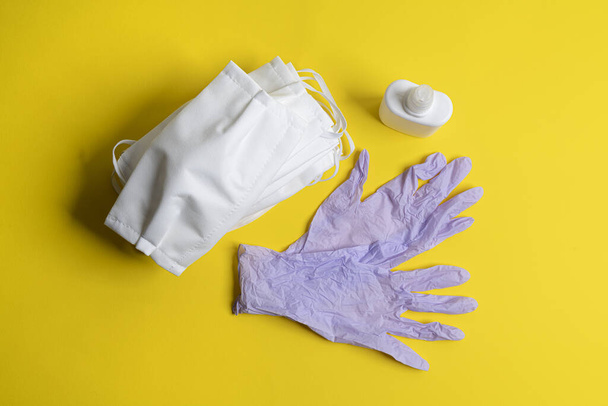 protective masks, disinfectant and disposable latex gloves on a colored surface - Photo, image