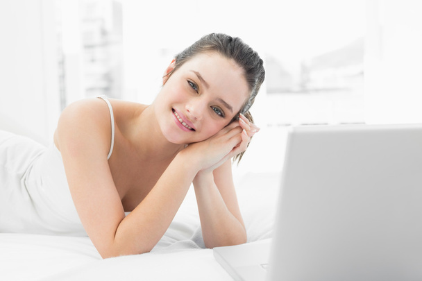 Smiling casual woman with laptop in bed - Foto, Imagen