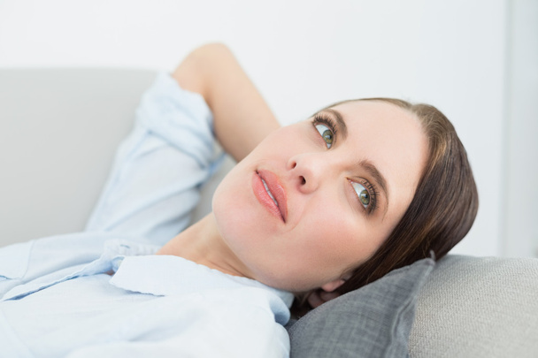 Close-up of a thoughtful woman relaxing on sofa - Foto, afbeelding