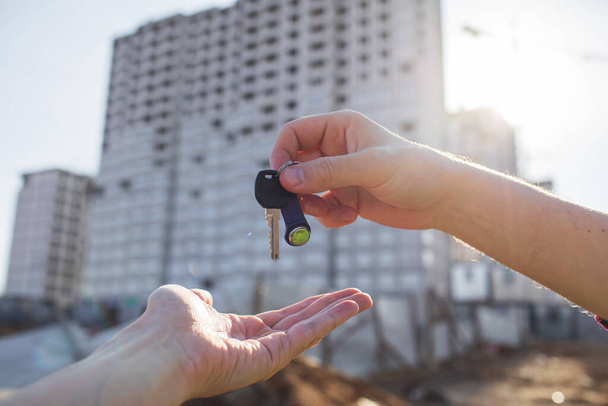 The keys to the apartment in hand on the background of new homes - Photo, Image