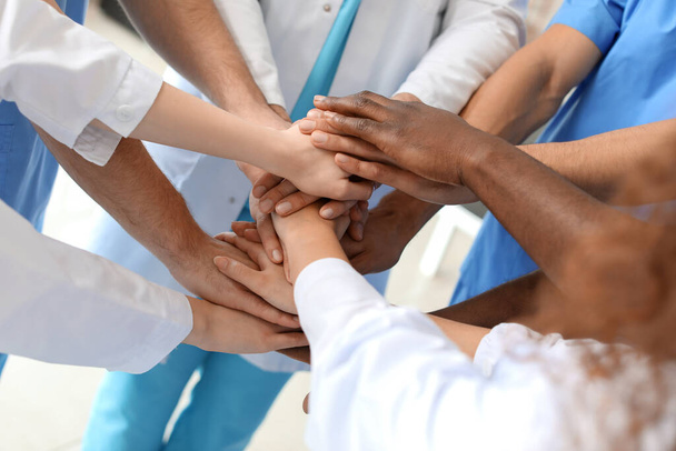 Grupo de médicos poniendo manos juntas en la clínica. Concepto de unidad - Foto, imagen