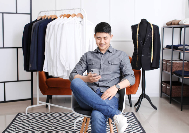 młody mężczyzna Azji stylista z telefon komórkowy w studio - Zdjęcie, obraz