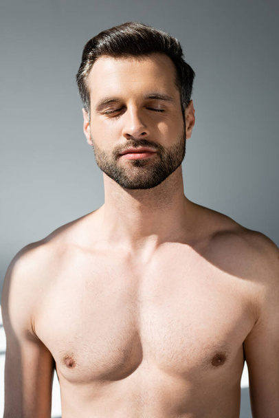 shirtloze en knappe man met gesloten ogen op grijs - Foto, afbeelding