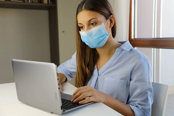 COVID-19 Pandemic Coronavirus Home Schooling E-learning Student Girl Mask Study from Home Laptop. Quarantine young woman studying from home for virus disease SARS-CoV-2. Smart school concept. - Photo, Image