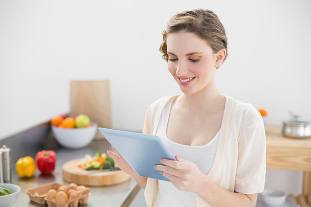 Content smiling woman working with her tablet in kitchen - Photo, image