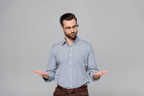 handsome businessman in glasses and shirt gesturing isolated on grey  - Фото, зображення