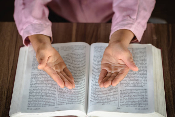 Детская рука во время молитвы за христианскую религию, Случайная женщина, молящаяся со Священной Библией, Религия концепции
. - Фото, изображение