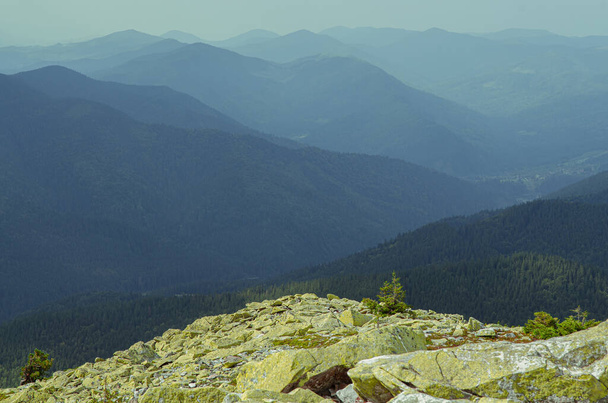 Sıradışı dağ yürüyüşleri. Sisteki yüksek sıradağların zeminine karşı yeşil oklarla kaplanmış devasa taşlar. - Fotoğraf, Görsel