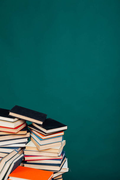 viele Stapel Bücher zum Unterrichten in der Schulbibliothek auf grünem Hintergrund - Foto, Bild