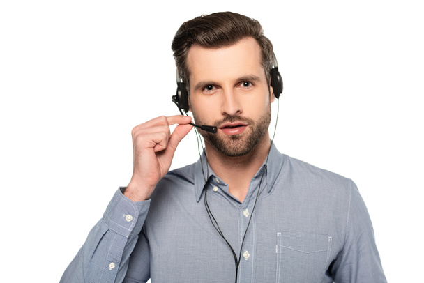 γενειοφόρος χειριστής αγγίζοντας ακουστικά και μιλώντας απομονωμένο σε λευκό   - Φωτογραφία, εικόνα