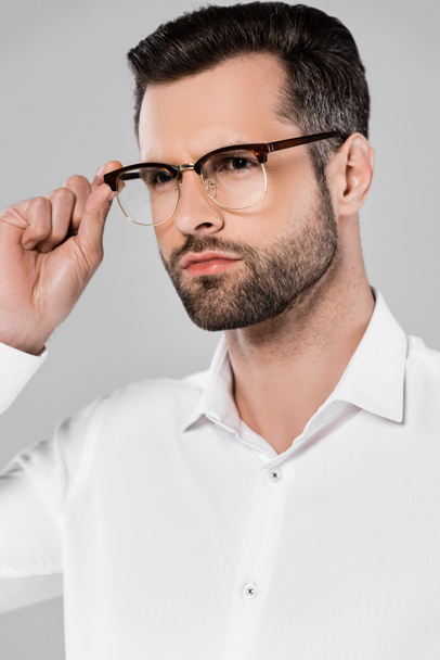 bearded and handsome businessman touching glasses isolated on grey  - Фото, изображение