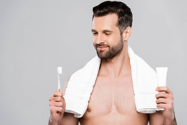 hombre barbudo feliz mirando cepillo de dientes aislado en gris
  - Foto, Imagen