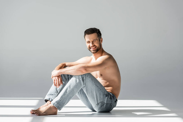 sunshine on happy and shirtless man in blue jeans sitting on grey  - Fotoğraf, Görsel