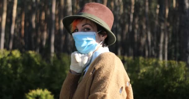Tyylikäs nainen, jolla oli naamio ja hanskat suojaamassa häntä sepelvaltimovirukselta. Käyttämällä sähkö skootteri kaupungin ja puiston olla turvallinen
. - Materiaali, video