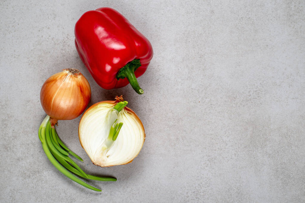 Frische rote Paprika und Zwiebeln auf einem grauen Stein. Hintergrund, Illustration für Werbung, Rezepte oder Kochbuch. - Foto, Bild