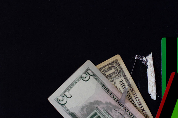 Líneas de cocaína, jeringa y billetes de dólar sobre fondo negro
. - Foto, Imagen
