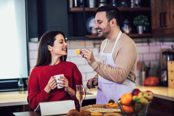 Kaunis nuori pari käyttää digitaalista tablettia ja hymyilee ruoanlaitossa kotona
 - Valokuva, kuva