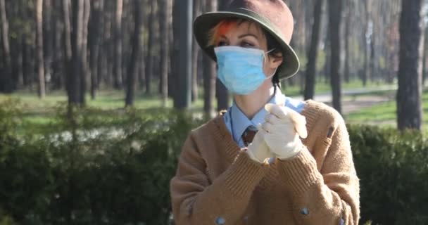 Egy elegáns nő maszkot és kesztyűt viselt, hogy megvédje a koronavírustól. Elektromos robogó használata a városban és a parkban, hogy biztonságos legyen. - Felvétel, videó
