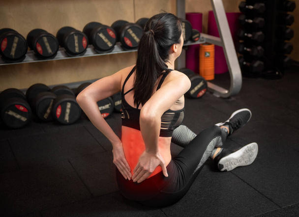 Woman having back pain while exercising in gym - Foto, Imagen