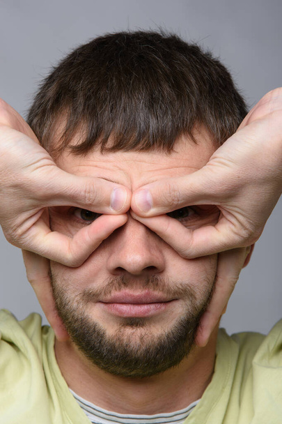 Portret mężczyzny, który własnymi rękami zrobił coś w rodzaju okularów na oczach europejskiego wyglądu - Zdjęcie, obraz