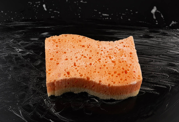 pano de laranja molhado retangular com espuma branca em um fundo preto, vista superior
 - Foto, Imagem