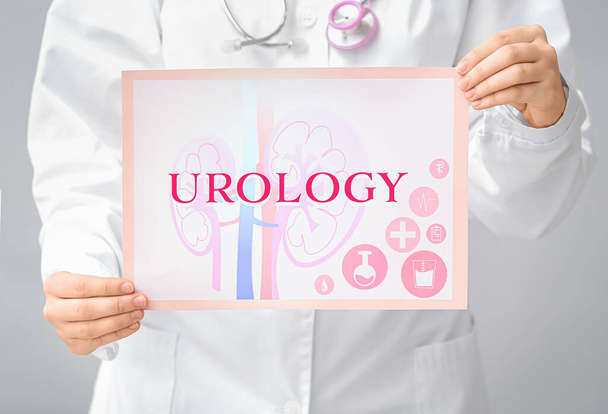 Doutor segurando papel com palavra UROLOGIA em fundo cinza, close-up
 - Foto, Imagem