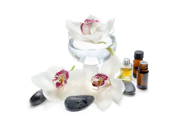 beautiful white orchids on glass jar with oil bottles and pebbles on white background  - Photo, image