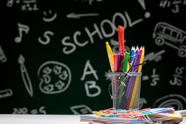School background with stationery accessories. Books, globe, pencils and various office supplies lying on the desk on a green blackboard background. - Foto, immagini