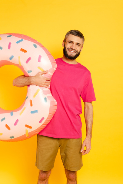 happy bearded guy in pink t-shirt with swim ring on yellow - Zdjęcie, obraz
