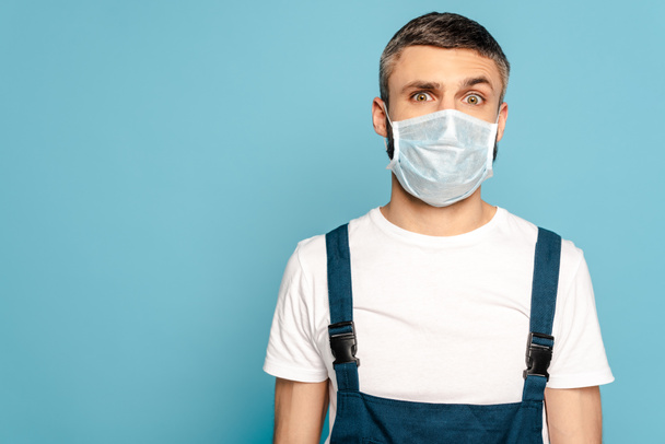 cleaner in medical mask on blue background - Φωτογραφία, εικόνα