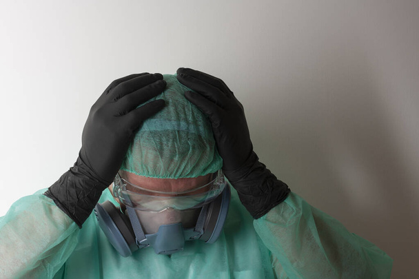 Enfermera de sexo masculino, con doble filtro de medio respirador facial máscara, gafas protectoras, gorra, bata, con equipo de protección personal para proteger contra el virus covid-19 en la UCI en el hospital
. - Foto, Imagen