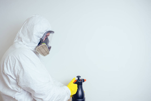 pest control worker spraying pesticides with sprayer in apartment copy spase white walls background - Photo, image