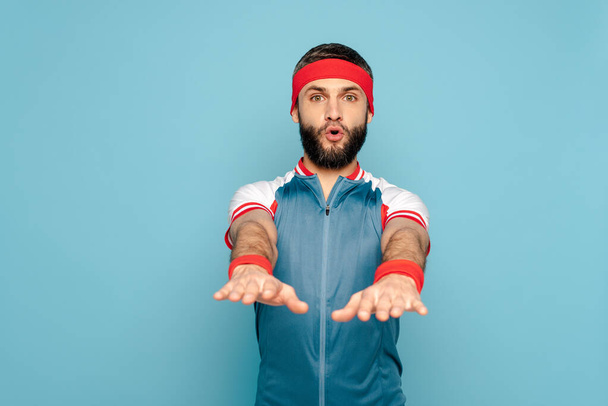 stylish sportsman exercising with outstretched arms on blue background - Photo, Image