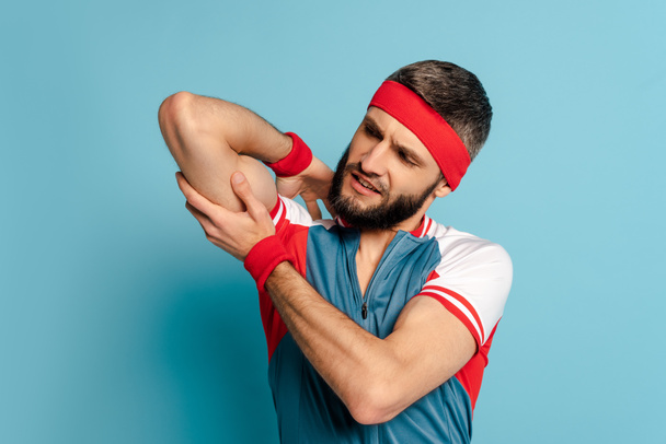 stílusos sportoló nézi bicepsz kék háttér - Fotó, kép