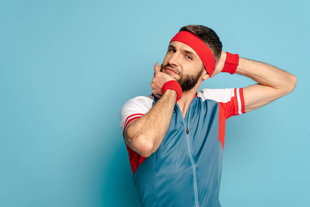 stylischer Sportler wärmt Kopf und Nacken auf blauem Hintergrund - Foto, Bild