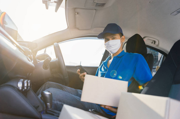 Asian Delivery man wearing mask send a package holding smartphone on front receiver shipping deliver cargo social distancing, Many parcel in hatchback car while the virus is spreading medical concept. - Foto, Bild