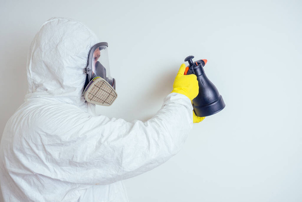 pest control worker spraying pesticides with sprayer in apartment copy spase white walls background - Foto, afbeelding
