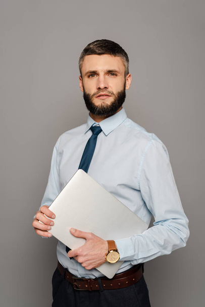 handsome bearded businessman with laptop on grey background - Photo, Image
