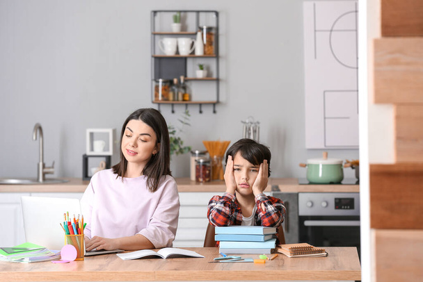 Mother with little boy unwilling to do homework in kitchen - Foto, imagen