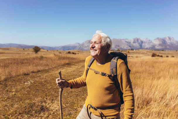 Старший чоловік під час походу по красивій сільській місцевості восени
. - Фото, зображення