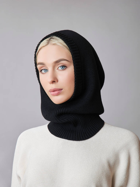 European Muslim woman with a blonde hair in a bonnet hood dressed on her head. Beautiful girl in sweater with soft skin, natural cosmetics - Φωτογραφία, εικόνα