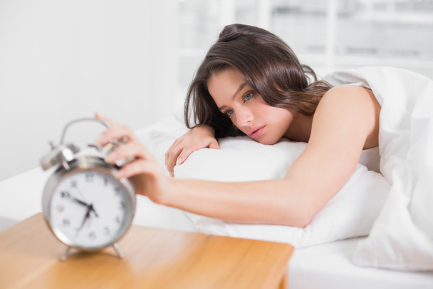 Woman in bed extending hand to alarm clock - Φωτογραφία, εικόνα