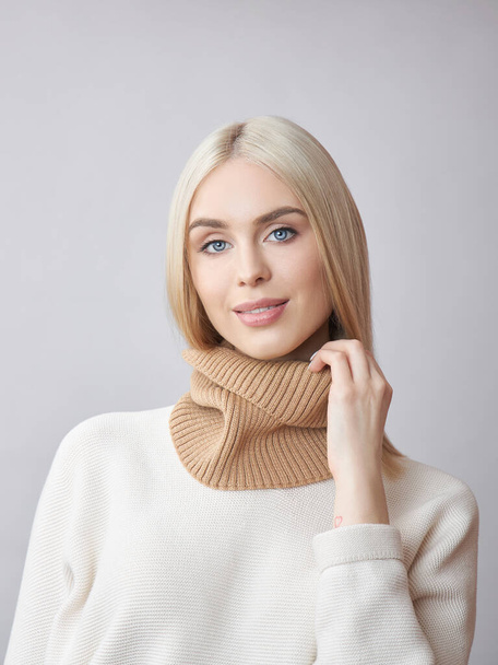 Blonde woman with long hair in a white sweater. Beauty portrait of a girl, natural cosmetics - Fotografie, Obrázek