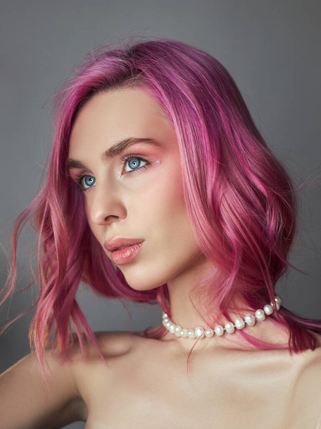 Beauty portrait woman with pink hair, creative vivid coloring. Bright colored highlights and shadows color on the face, a girl with jewelry. Dyed hair in the wind - Fotografie, Obrázek